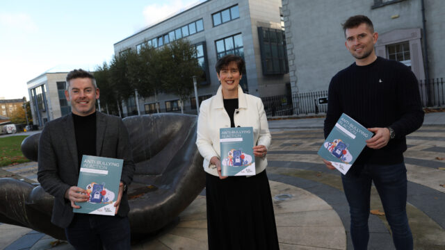 This is a photo of Colm Canning, Norma Foley TD, and Colm Canning. They are smiling and holding booklets titled "Anti-Bullying in Action" towards the camera.